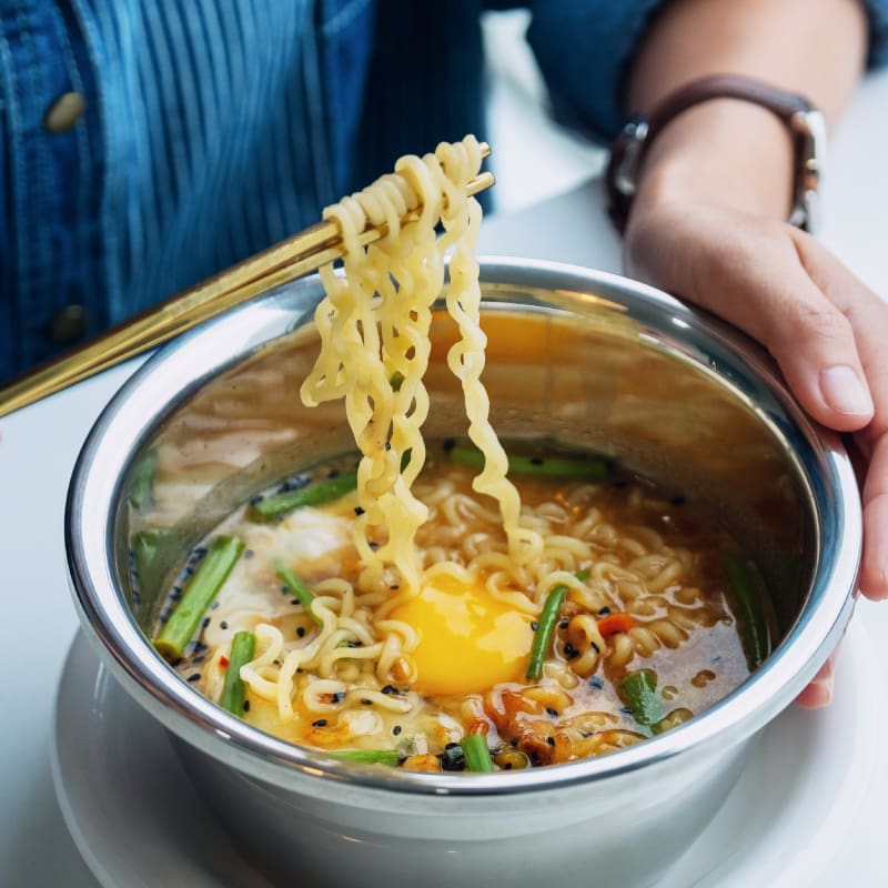 lake-crest-village-ramen-dining Bowl of ramen with noodles being lifted with chopsticks